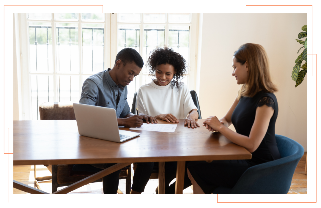 A man and a woman are sitting at a table with a laptop.