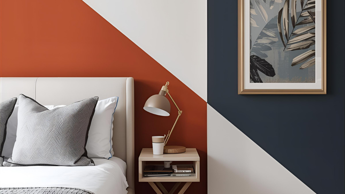 Bedroom with diagonal color-blocked walls: orange, white, and navy blue. Bed, lamp, and artwork.