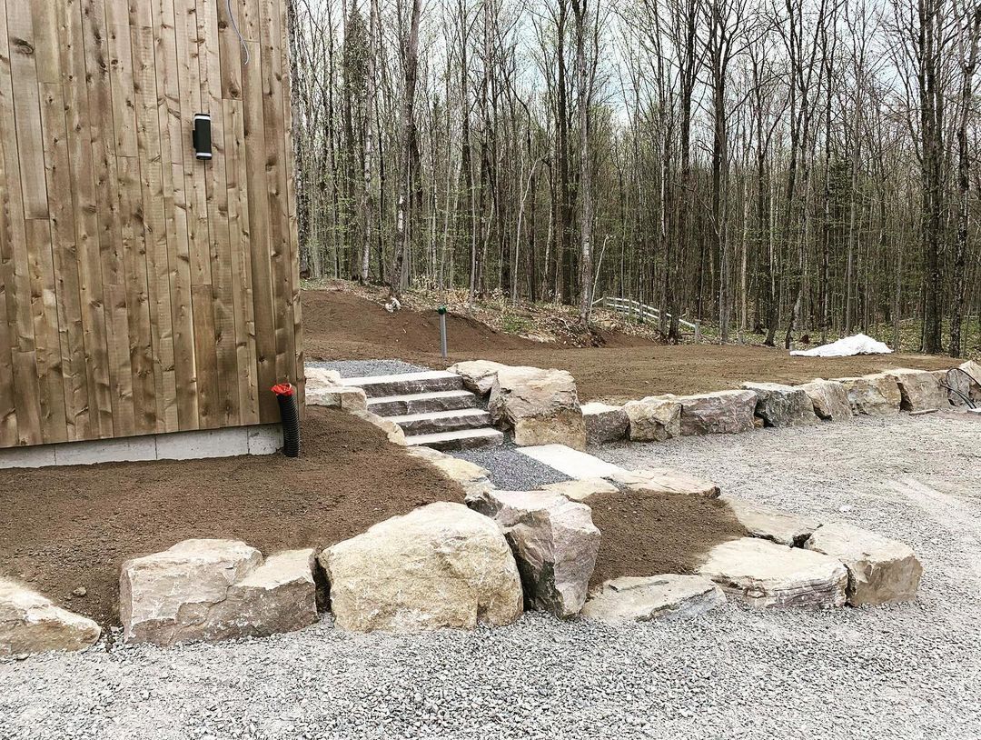Un bâtiment en bois auquel on accède par des escaliers est entouré de rochers et de graviers.