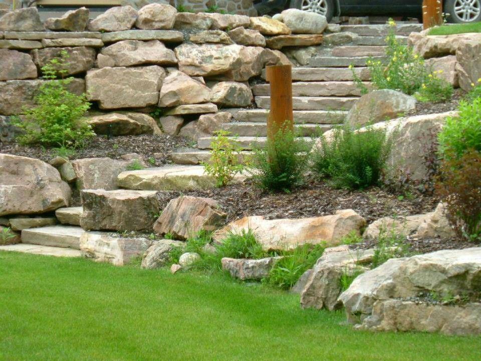 Une voiture est garée dans une allée à côté d'une paroi rocheuse et d'un escalier.