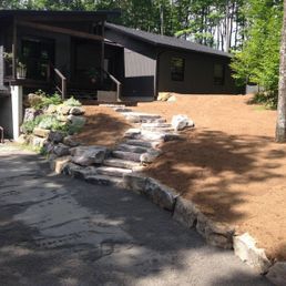 Une maison avec des escaliers qui y mènent est entourée d'arbres et de terre.