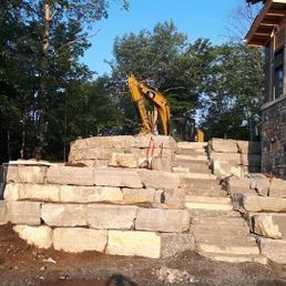 Une excavatrice jaune est assise au sommet d'un tas de roches.