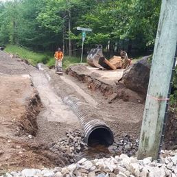 Un homme se tient à côté d'un gros tuyau dans la terre.