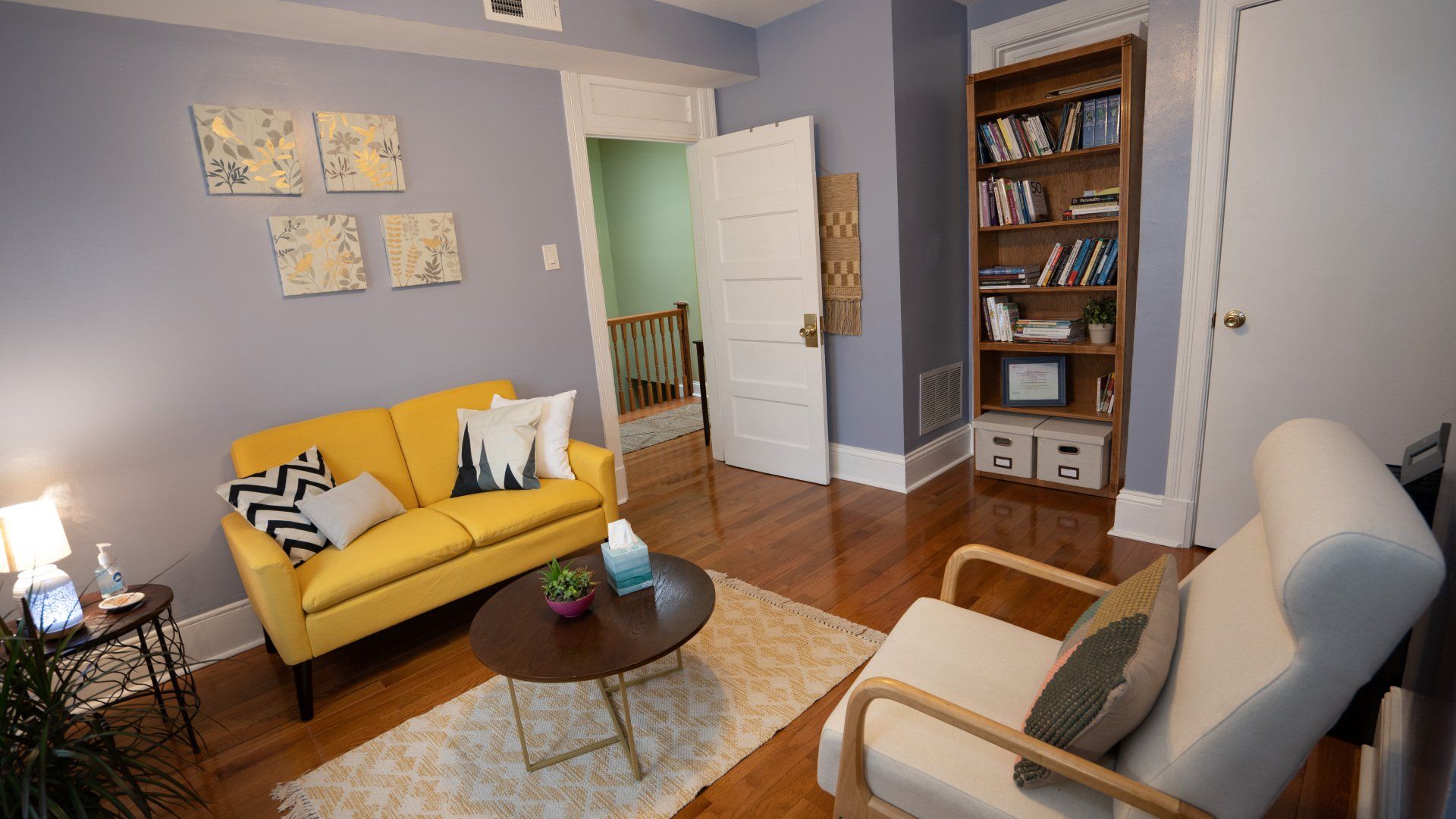 A therapy office with a yellow couch and a white chair.