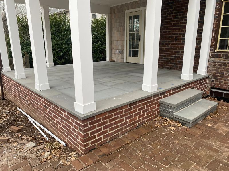 A brick porch with white pillars and steps