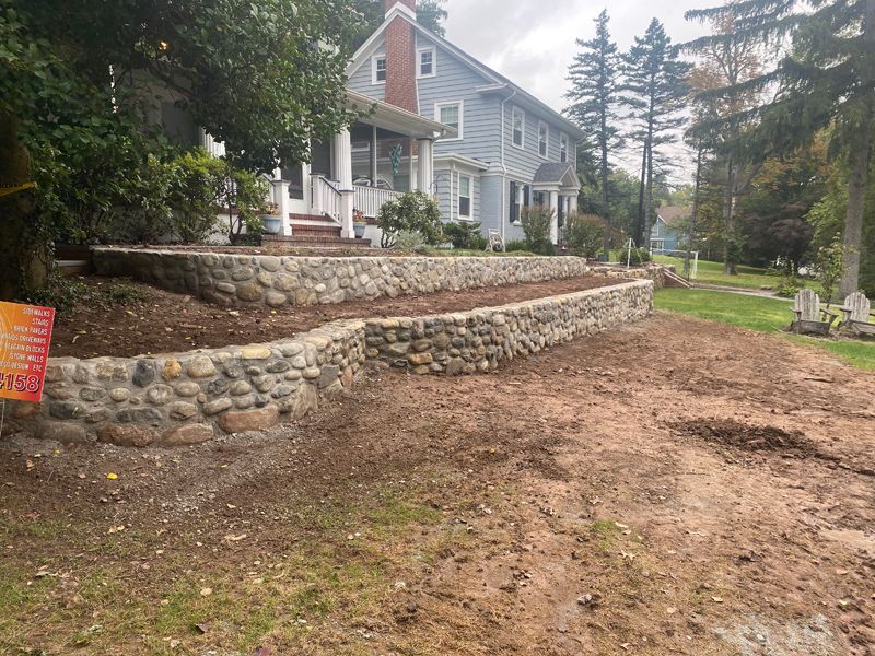 A large house with a stone wall in front of it.