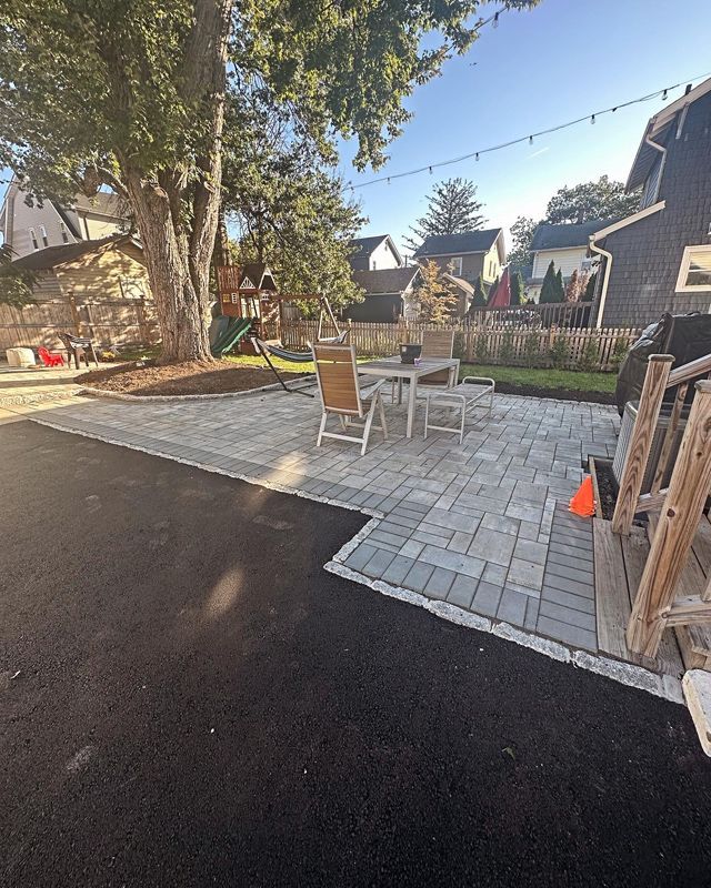 A patio with a table and chairs in the backyard of a house.