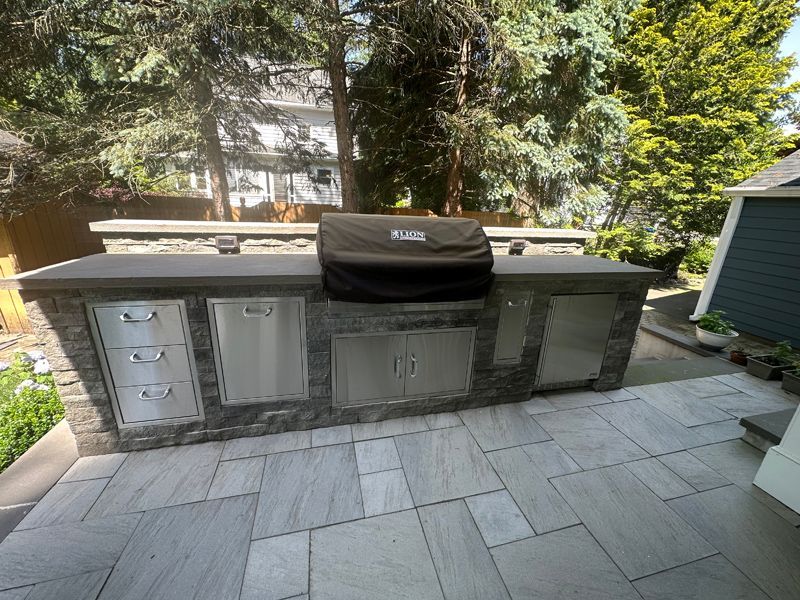 A stainless steel grill is sitting on top of a tiled patio.
