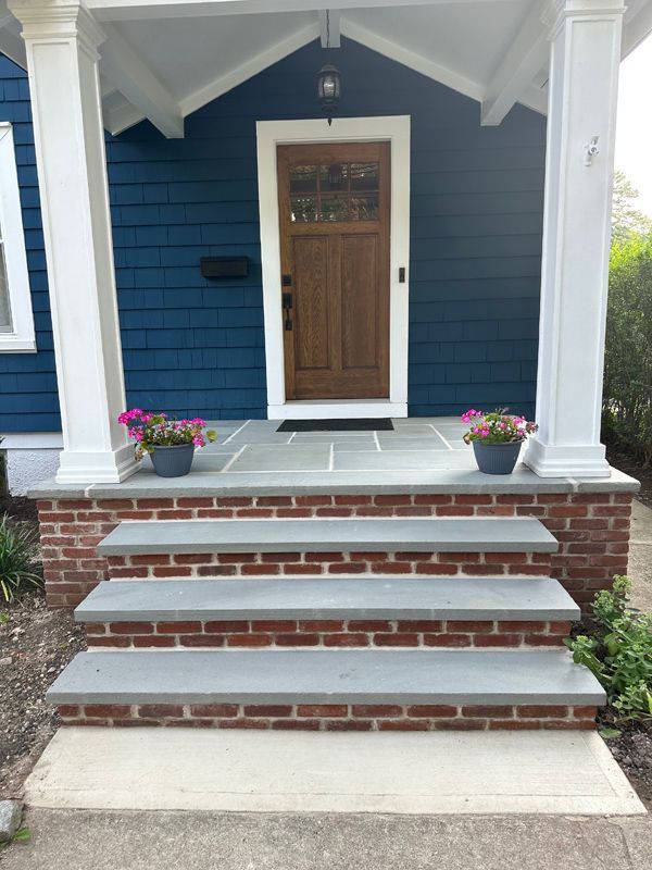 A blue house with a wooden door and brick steps