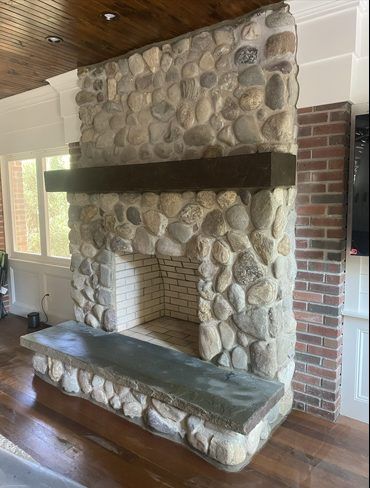 A stone fireplace with a wooden mantle in a living room.