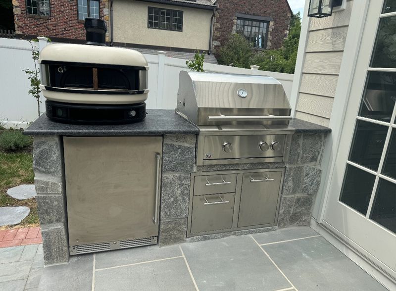 A pizza oven is sitting on top of a stainless steel grill.