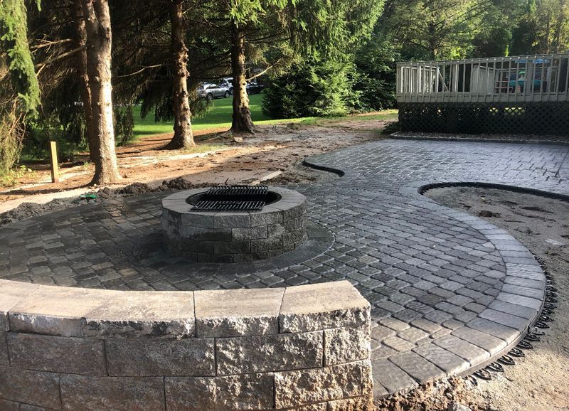 A fire pit is sitting in the middle of a brick patio.