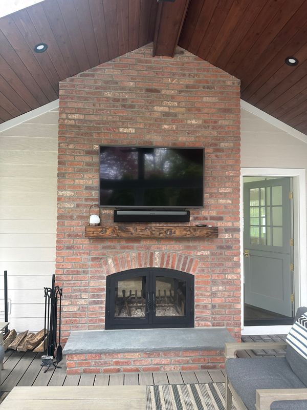 A brick fireplace with a flat screen tv mounted above it.