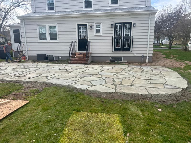 A white house with a stone patio in front of it.