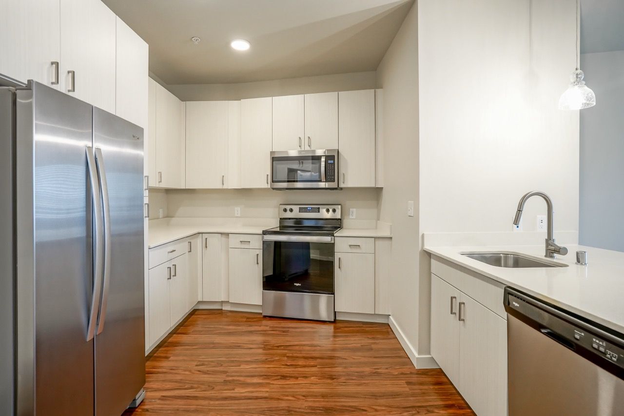 Modern kitchen with stainless steel appliances, white cabinets, and a double sink.