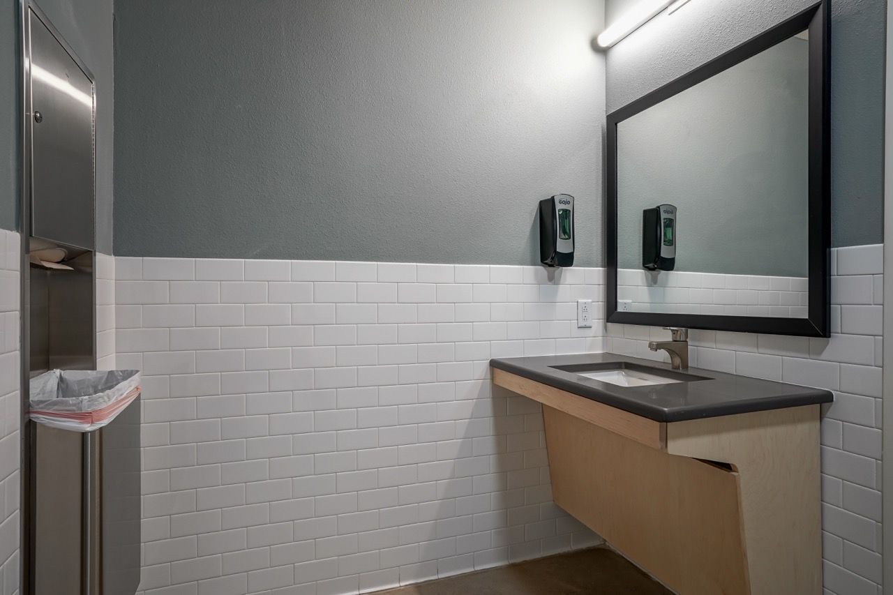 Bathroom sink area in an apartment with a framed mirror, soap dispensers, and white subway tile.