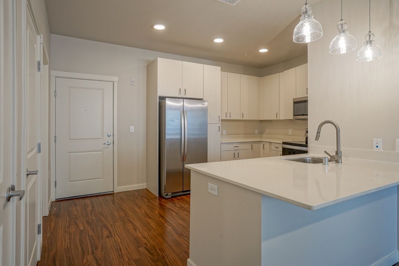 Open-concept kitchen with white cabinets, stainless steel refrigerator, and an island.
