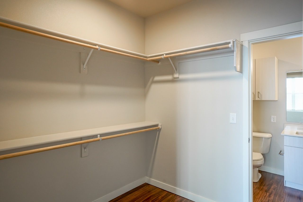 Walk-in closet with double hanging rods and shelves; doorway to bathroom.