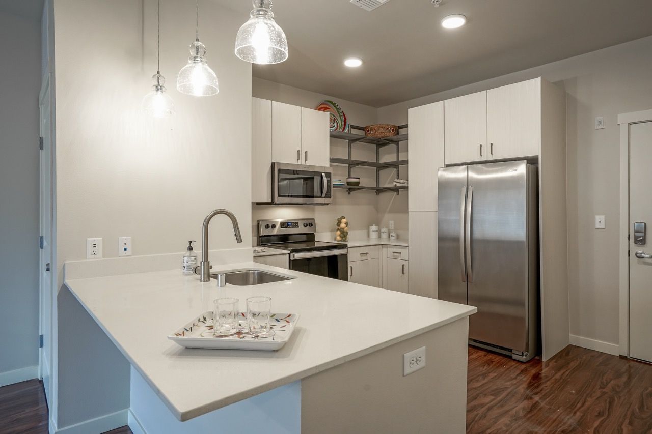 Modern kitchen with white cabinets, stainless steel appliances, and an island with a sink.