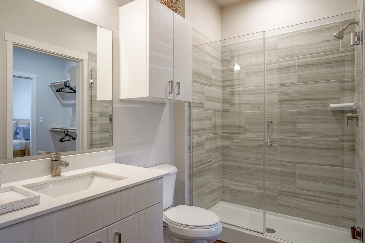 Bathroom with vanity, mirror, toilet, and glass-enclosed shower
