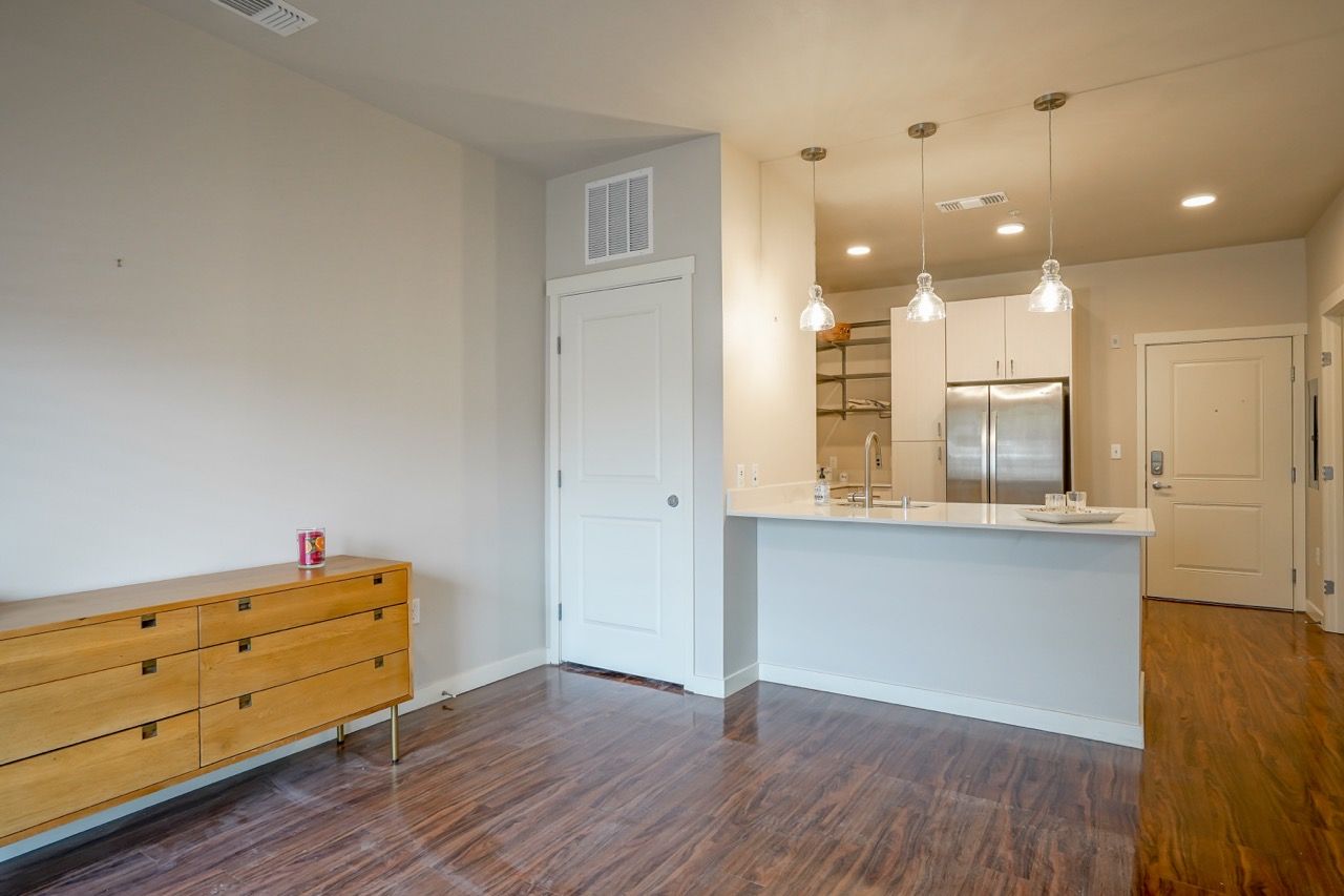 Open-concept living space with kitchen island, hardwood floors, and stainless-steel appliances.