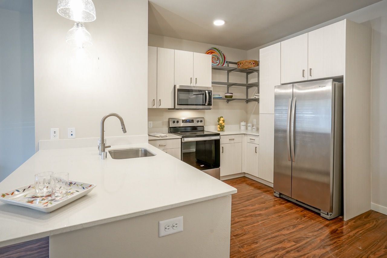 Modern kitchen with stainless steel fridge, range, microwave, and white cabinets.