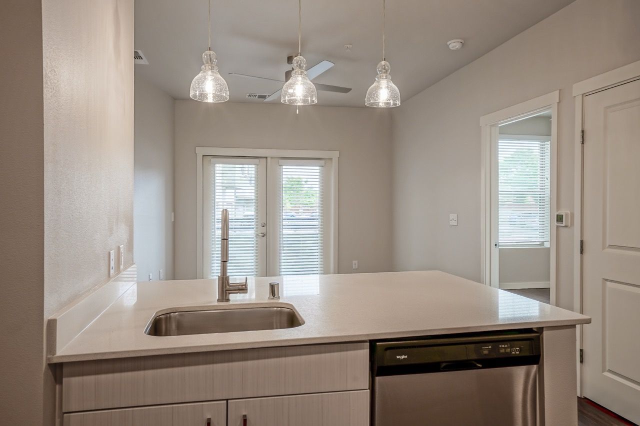 Modern kitchen with an island, sink, dishwasher, and glass pendant lights.