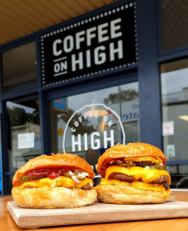 Two Hamburgers on a Cutting Board in Front of a Coffee on High Sign — Coffee on High in Wauchope, NSW