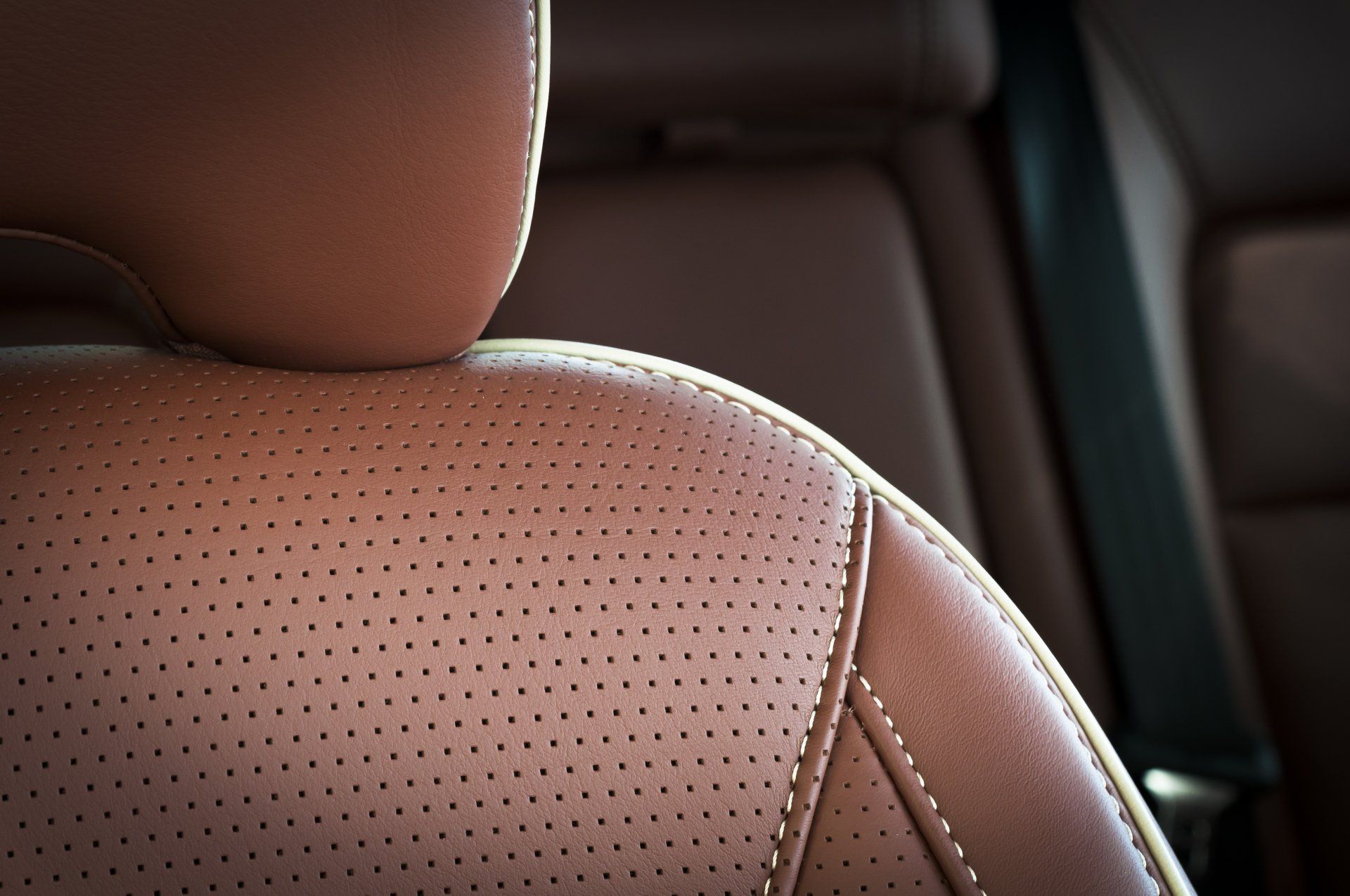 Part of red leather car seat with the unfocused car interior on the background