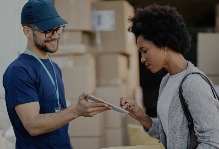 A delivery man is giving a tablet to a woman.