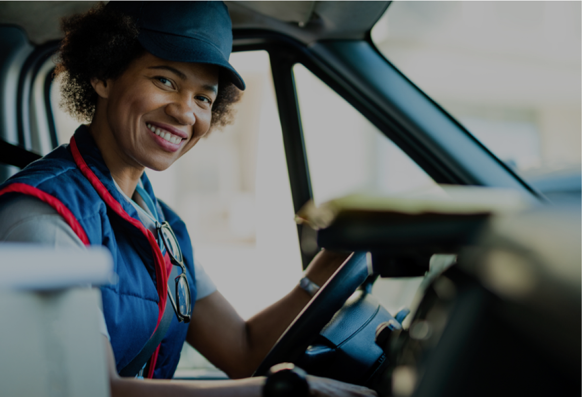 A woman is sitting in the driver 's seat of a van and smiling.