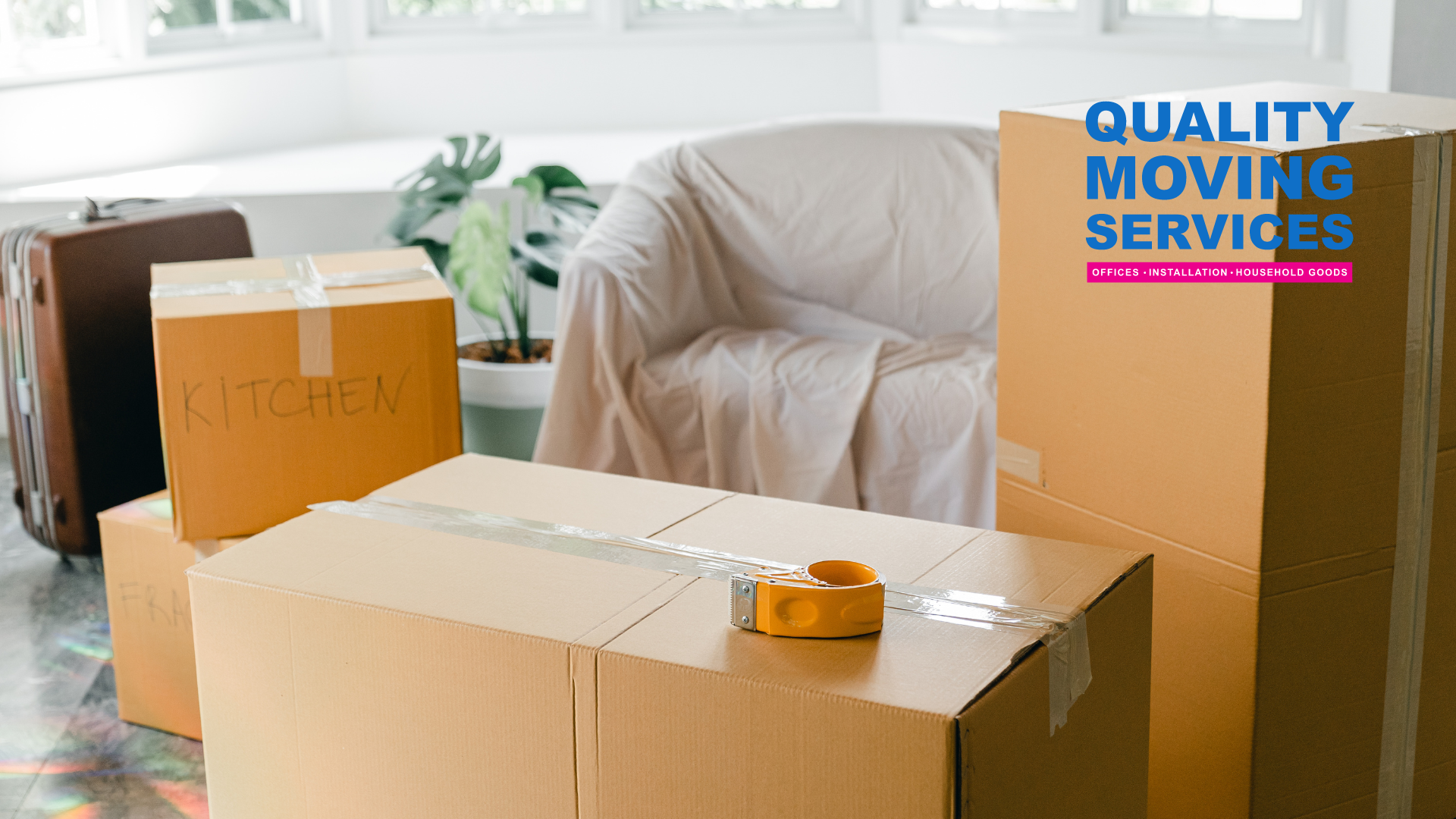 A living room filled with cardboard boxes and a chair covered in a white blanket.