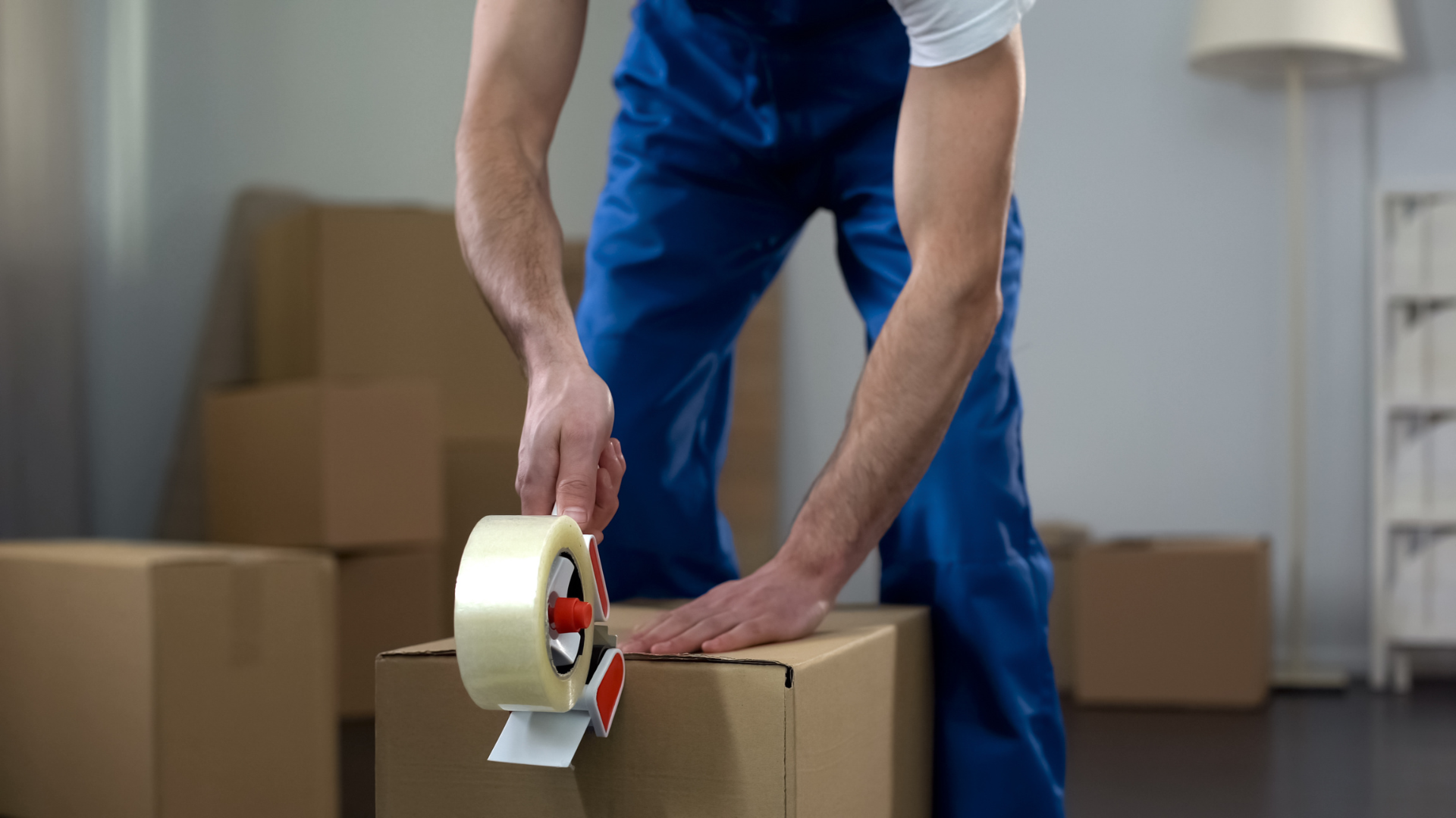 A man is taping a cardboard box with tape.