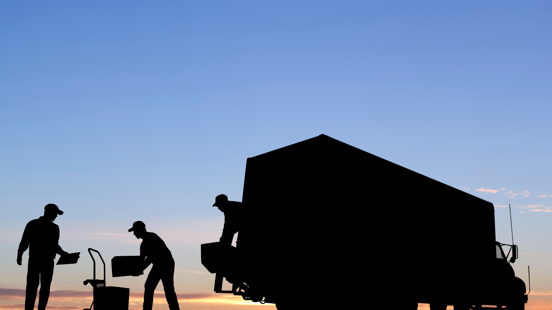 A man is loading boxes into the back of a red truck.