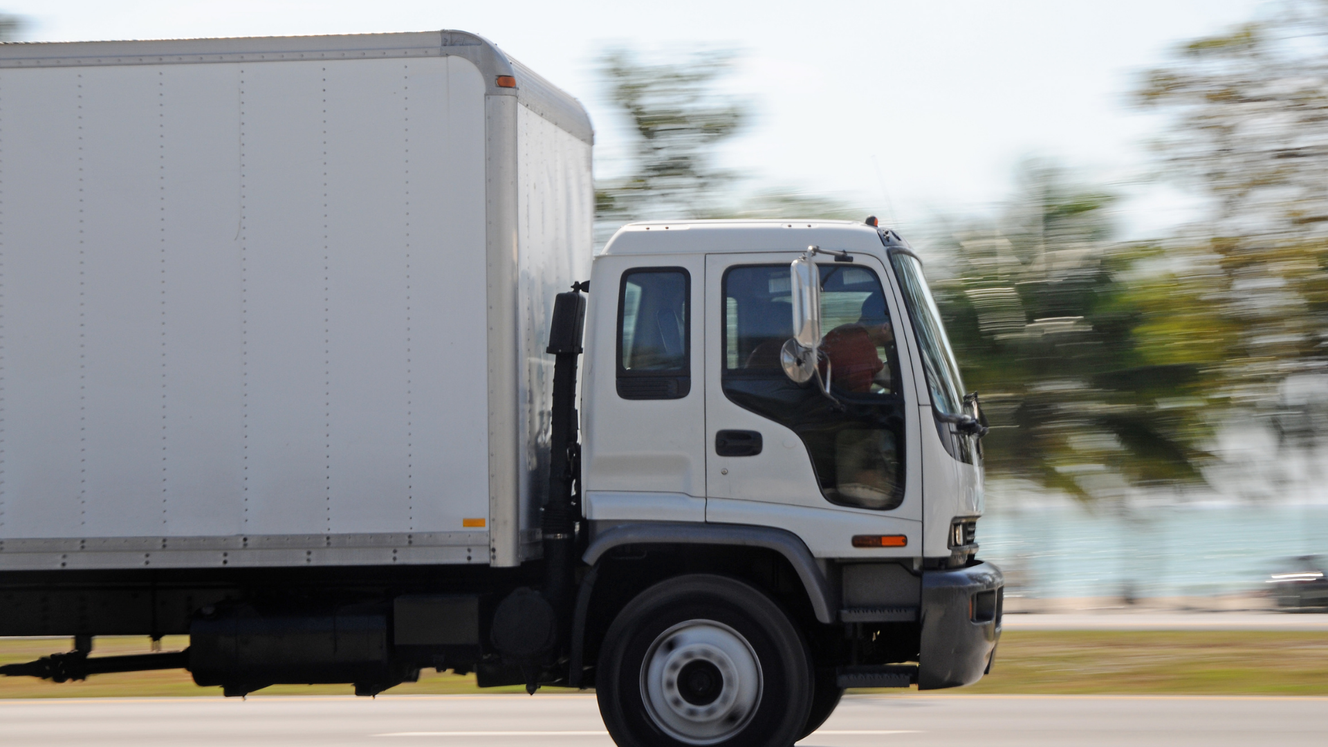A white box truck is driving down a road.