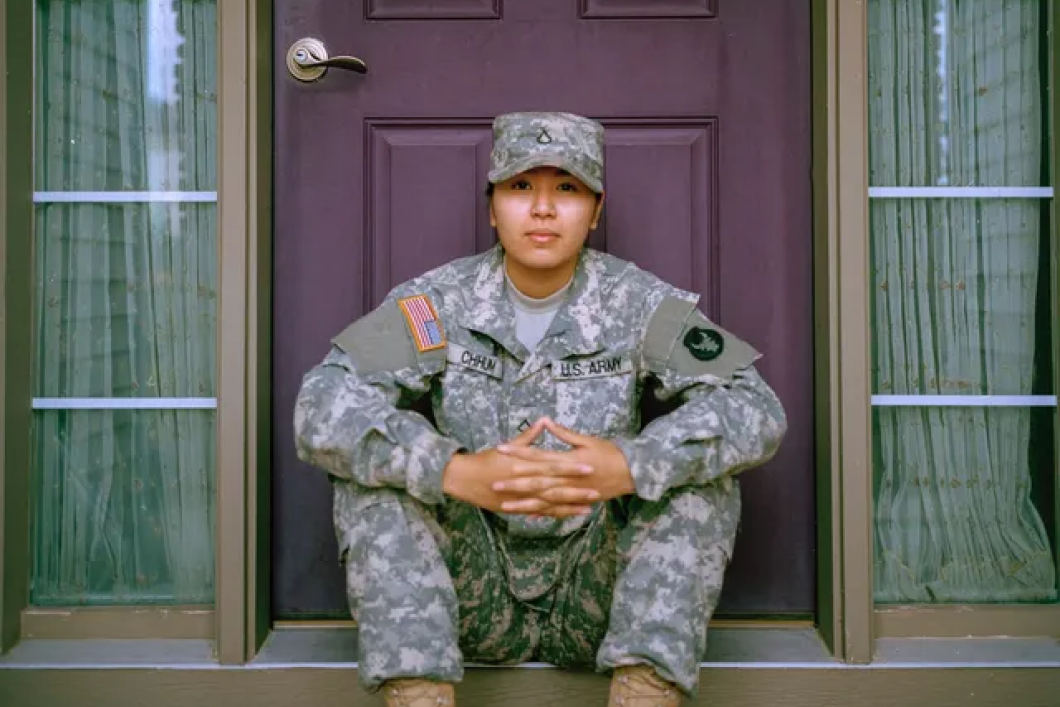 A soldier is sitting on the steps of a purple door.