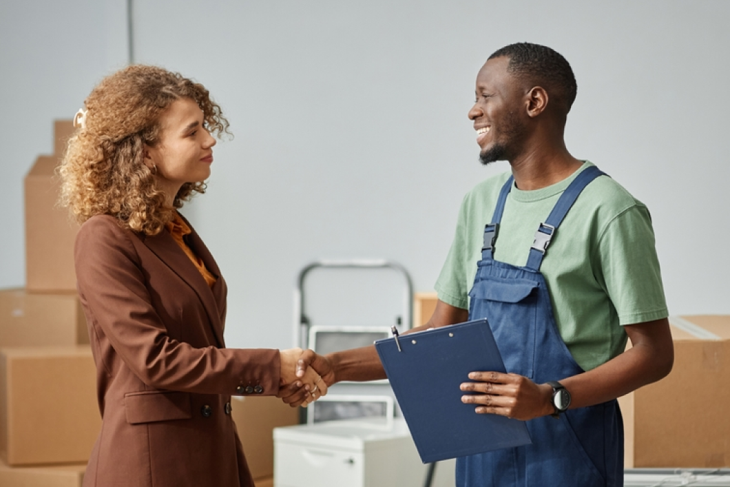 A man in overalls is shaking hands with a woman in a suit.