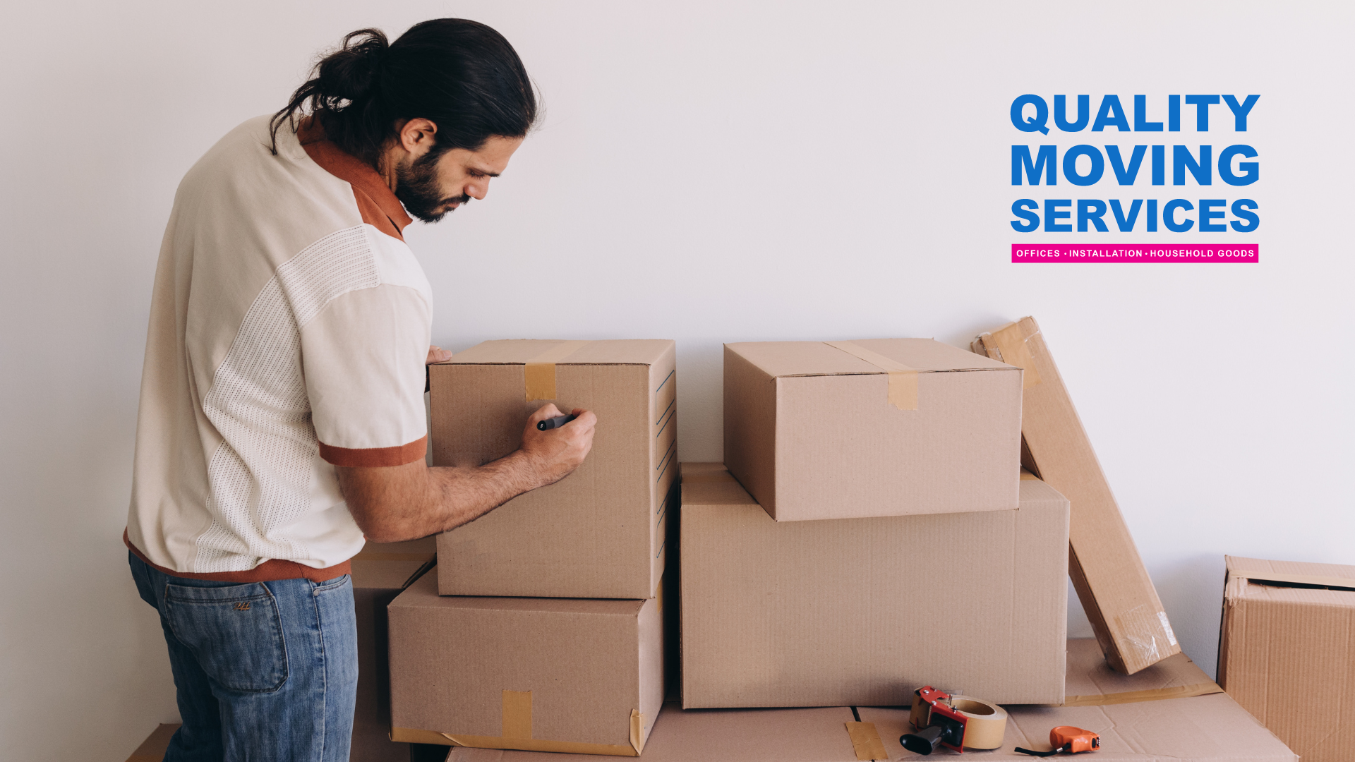 A man is standing next to a pile of cardboard boxes.