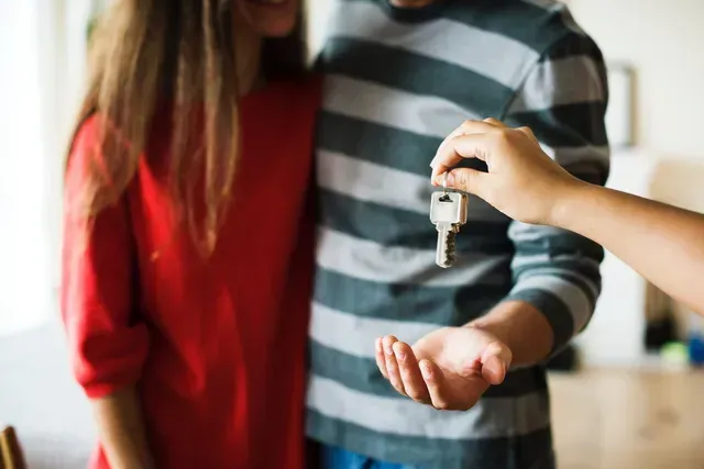 A man is handing a key to a woman.