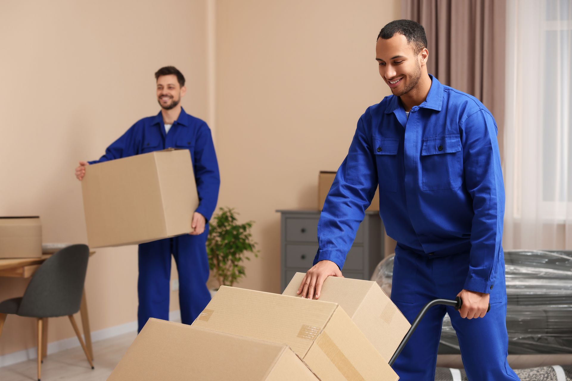 A man and a woman are carrying boxes in a room.