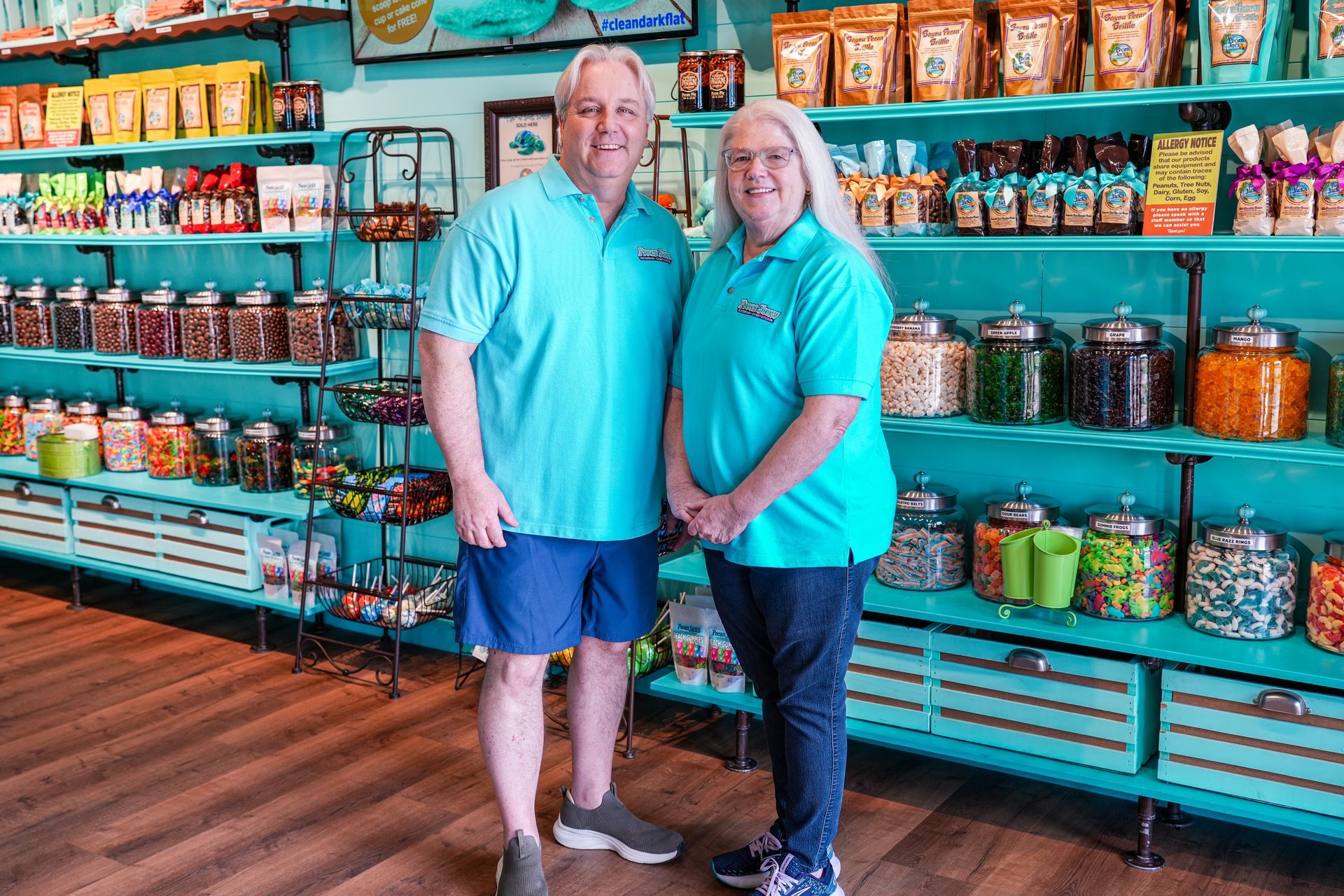 A man and a woman are standing in front of a candy store.