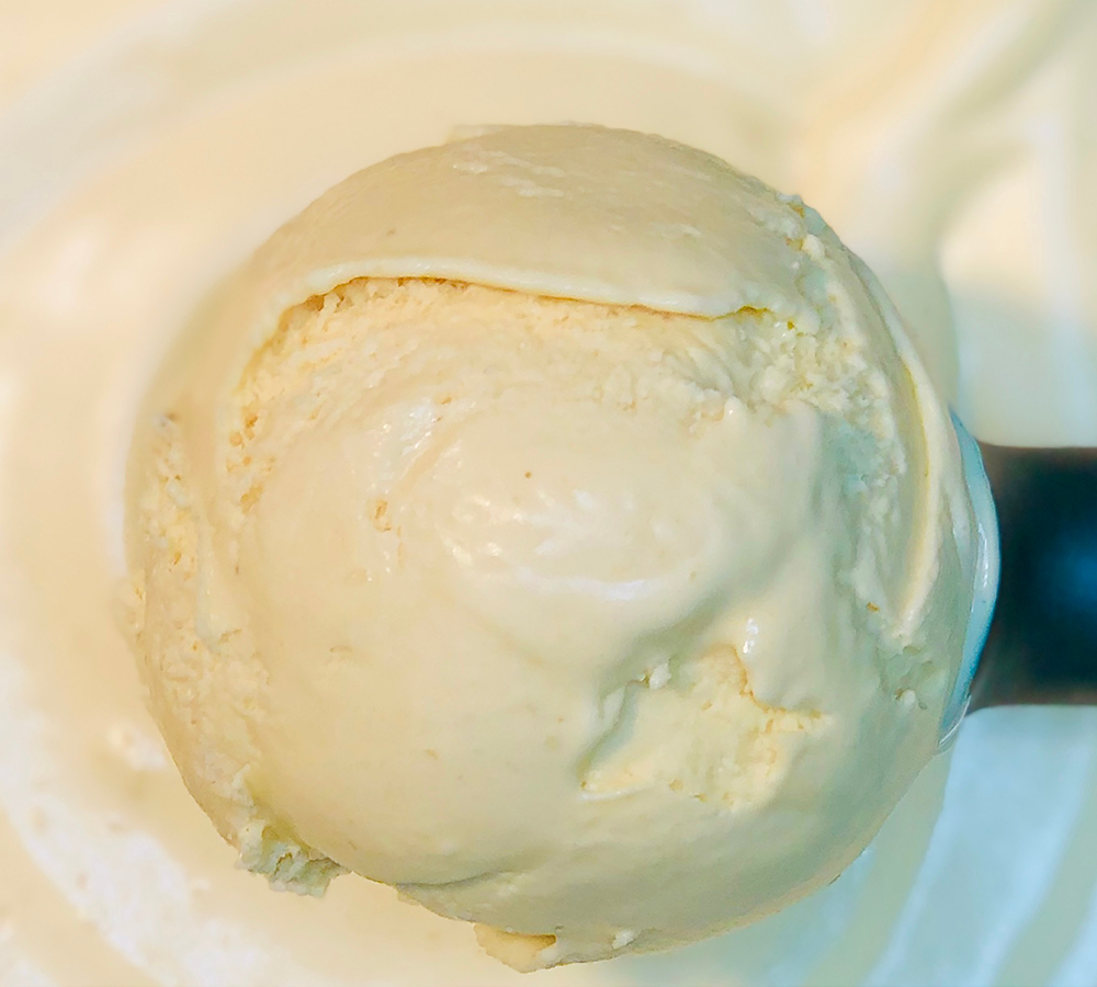 A close up of a scoop of vanilla ice cream on a plate.