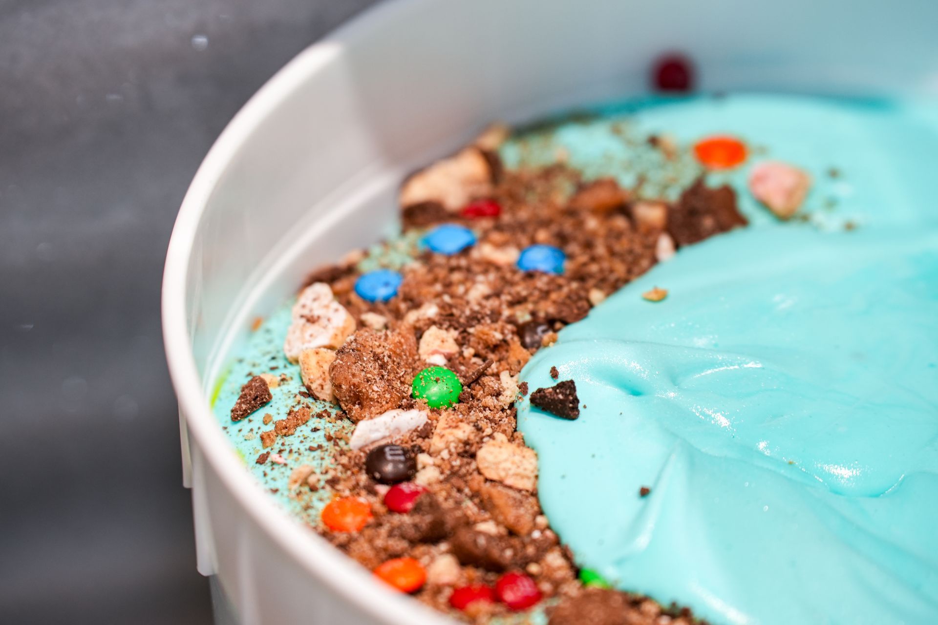 A close up of a bowl of ice cream with candy on top.