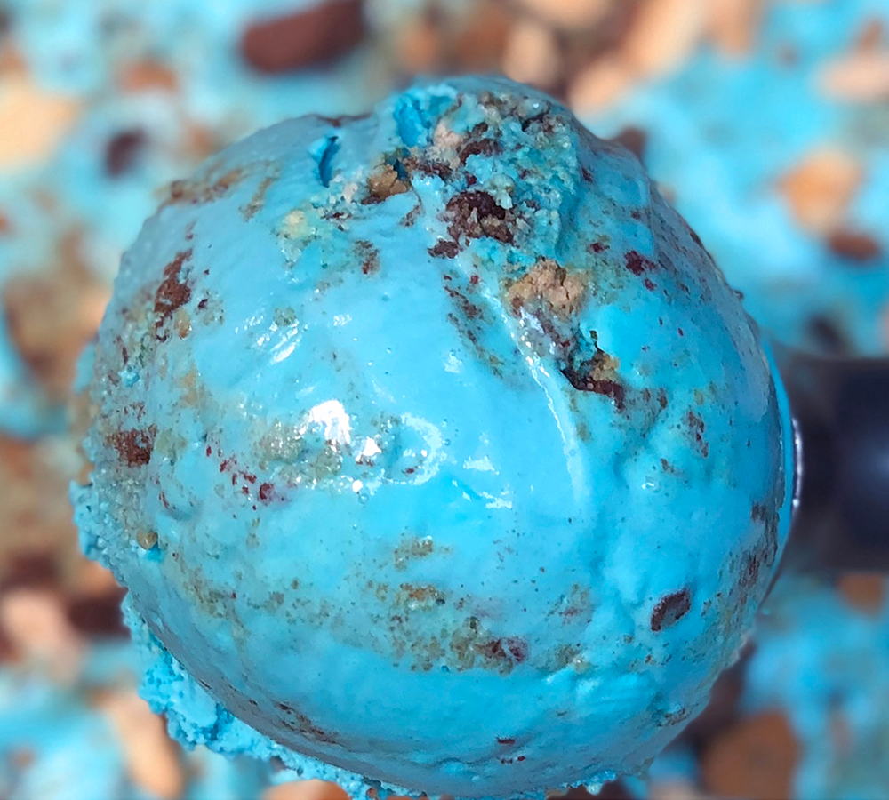A close up of a scoop of blue ice cream on a spoon.