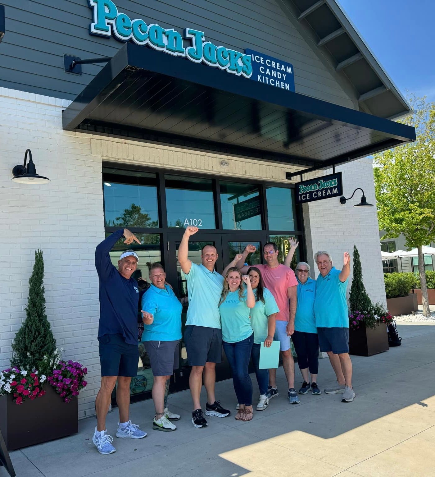 A group of people standing in front of a pecan jerry ice cream shop