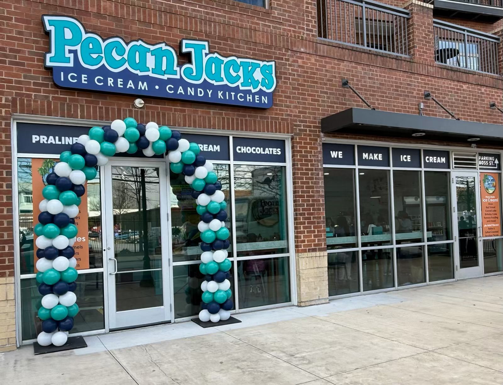 Pecan Jack's ice cream shop entrance, teal and white balloon arch, brick building.