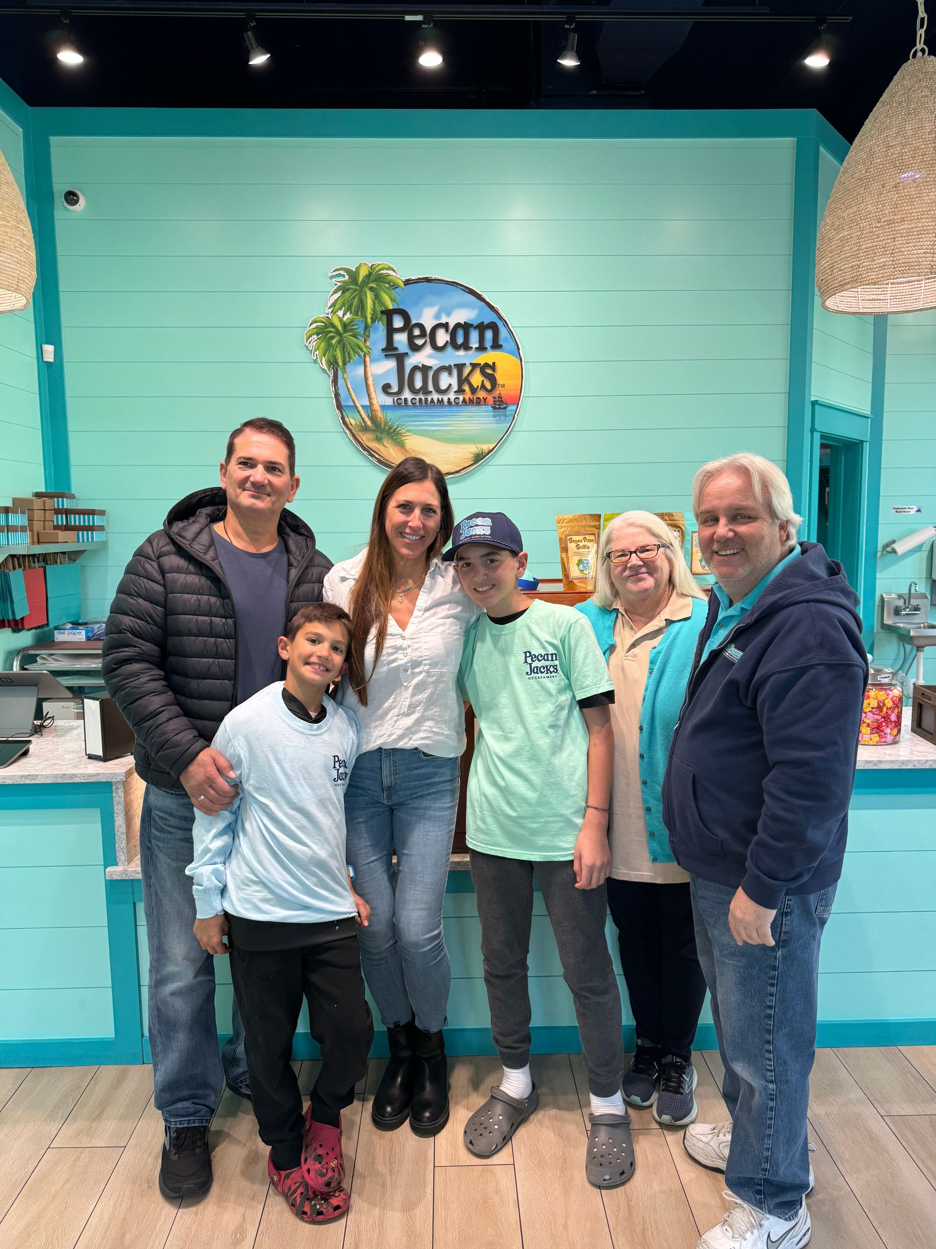 A group of people are posing for a picture in front of a sign that says pecan jacks.