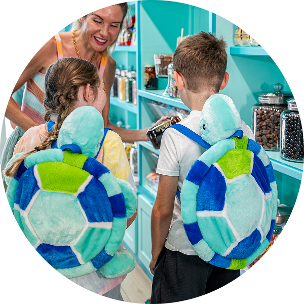 A group of children wearing turtle backpacks in a store