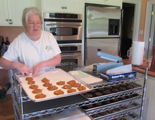 A woman is putting cookies on a tray in a kitchen