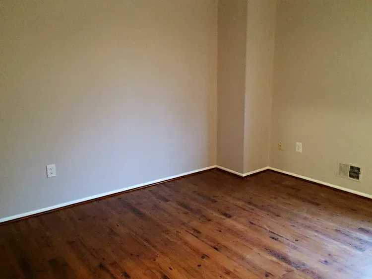 Empty room with wood floors and tan walls.